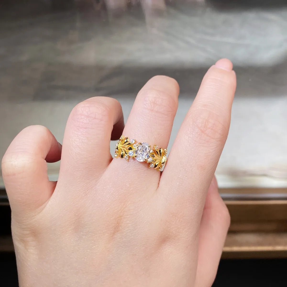 Bague dorée sertie de pierres transparentes, portée sur la main