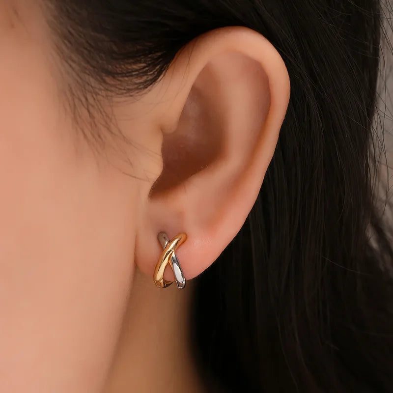 Boucles d’oreilles croisées en forme de « X » dorées, portées sur l’oreille