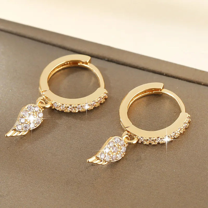 Créoles pendantes dorées à anneau pavé de zirconiums, petites ailes en pendentif.