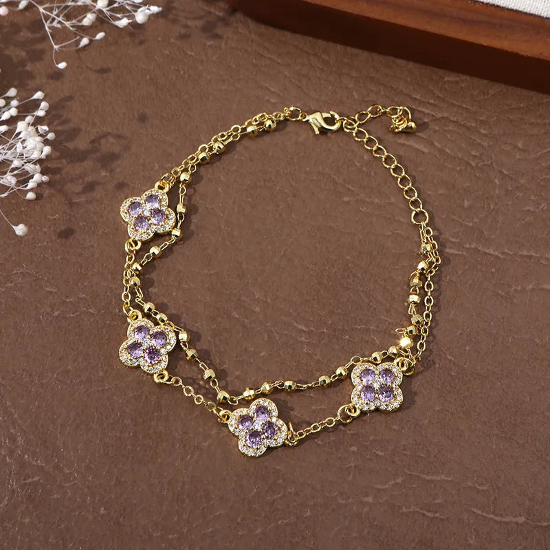 Bracelet double chaîne doré avec breloques trèfles en zirconium violet, chaînons fins.