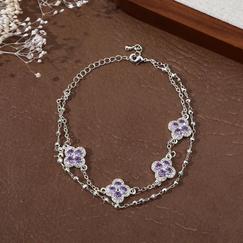 Bracelet double chaîne argenté avec breloques trèfles en zirconium violet.