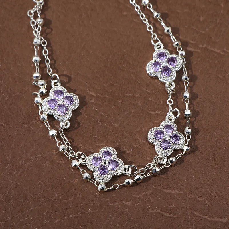 Bracelet double chaîne argenté, breloques trèfles en zirconium violet, maillons brillants.