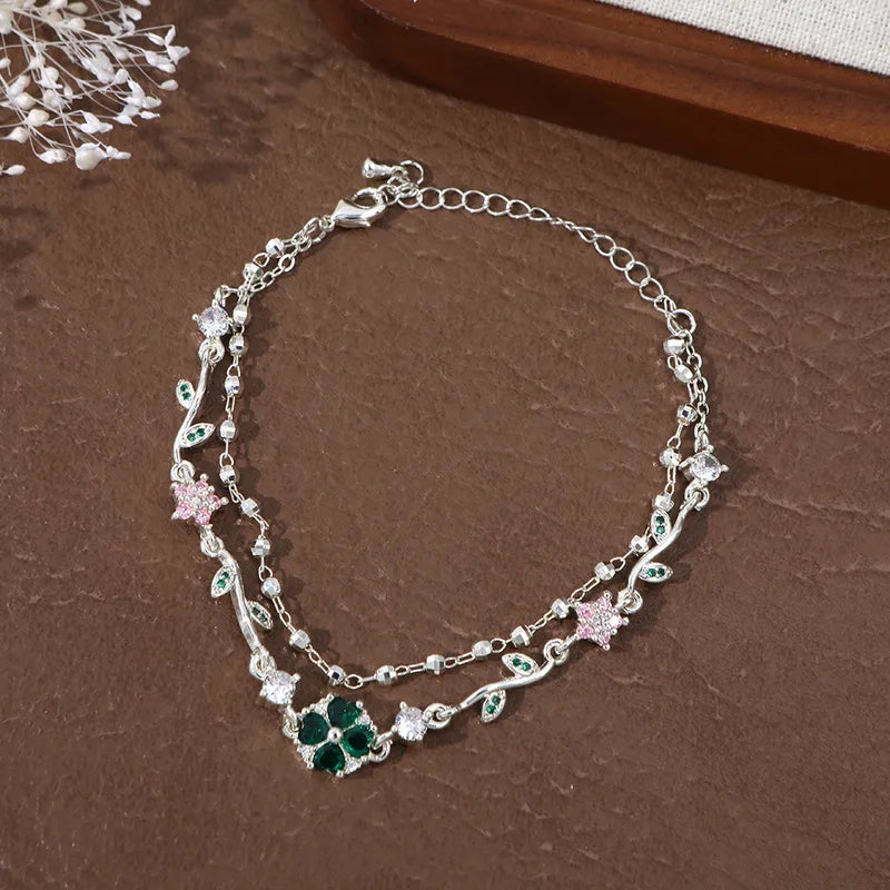 Bracelet double chaîne argentée, trèfle vert émeraude central et fleurs rose poudré
