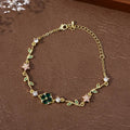 Bracelet double chaîne dorée, trèfle émeraude central, feuilles vertes et fleurs rose