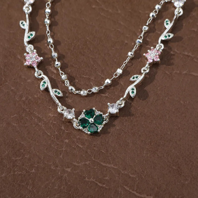 Bracelet double chaîne argentée avec trèfle vert émeraude central et fleurs rose poudré