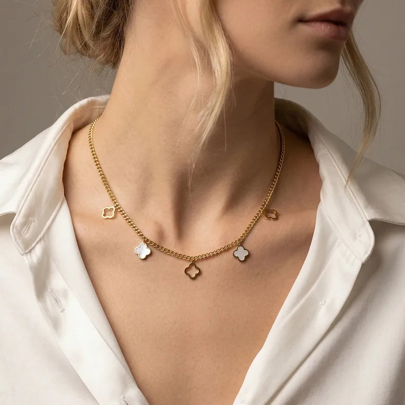 Collier doré à pendentifs trèfles nacrés porté avec une chemise blanche