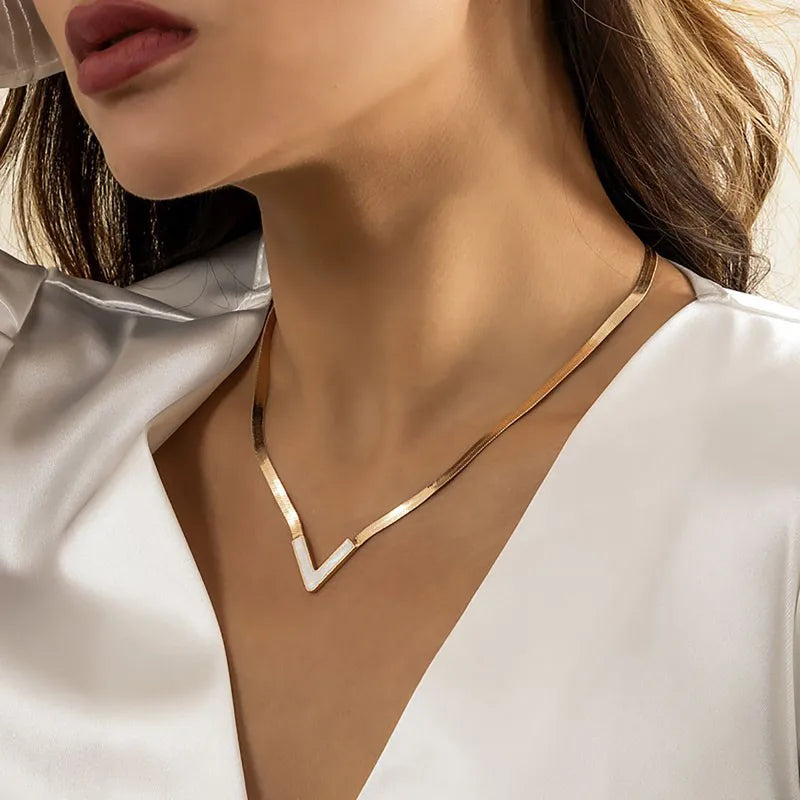 Collier plaqué or à chaîne fine et pendentif en V nacré, porté près du cou
