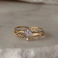 Bague dorée réglable à double rang dentelle filigranée avec pierre violette centrale.