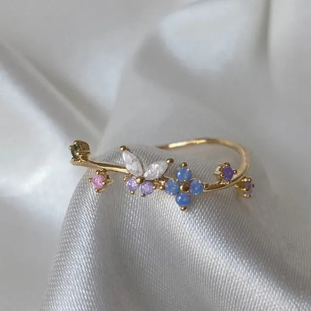 Bague dorée ajustable motif papillon et cristaux roses et bleus sur l’anneau
