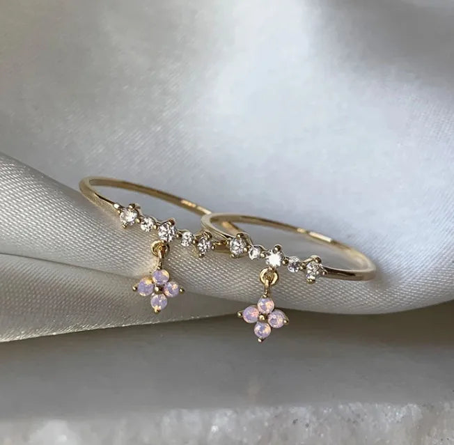 Bague ajustable dorée avec breloques fleurs roses et pierres claires, style tige fine.