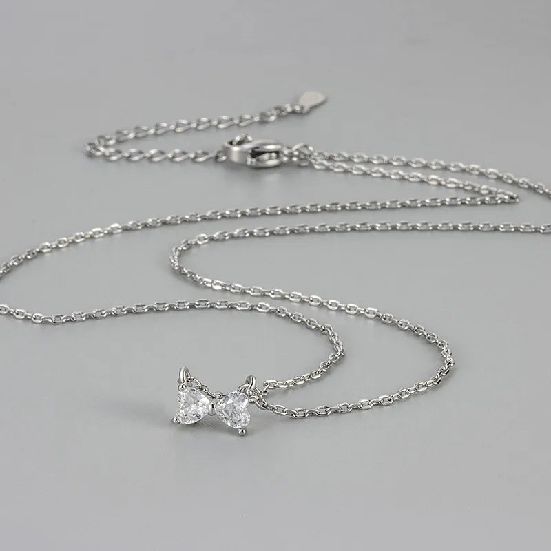 Collier argenté à pendentif nœud papillon en zircons, chaînes fines à maillons.