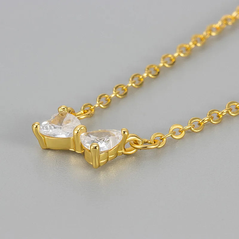 Collier doré à pendentif nœud papillon serti de zircons transparents, finition brillante.