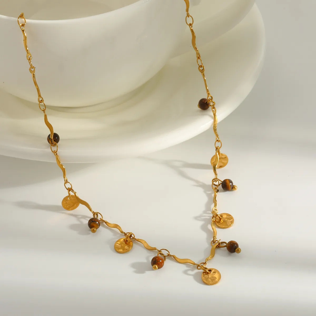 Collier chaîne dorée ondulée avec pastilles martelées et petites billes brunes