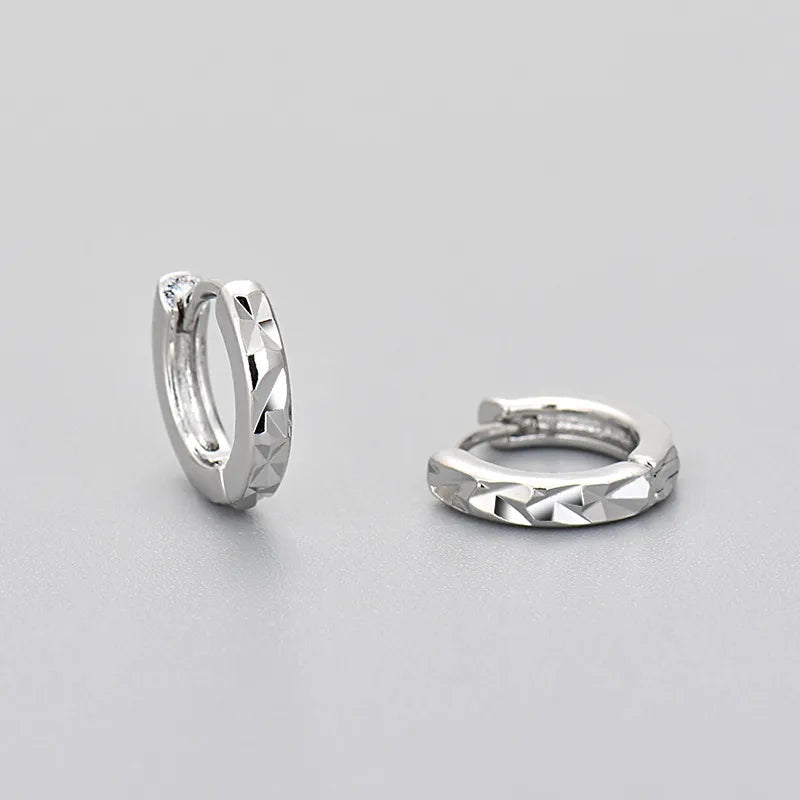 Créoles en argent effet diamanté, anneaux texturés aux facettes géométriques.