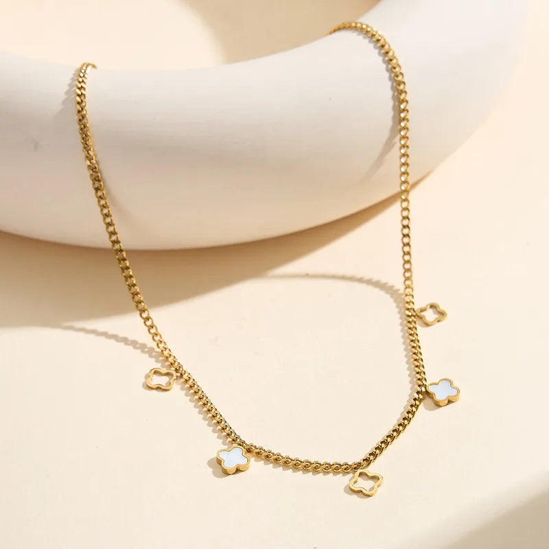 Collier doré à chaîne fine et pendentifs trèfles nacrés, angle sur le devant