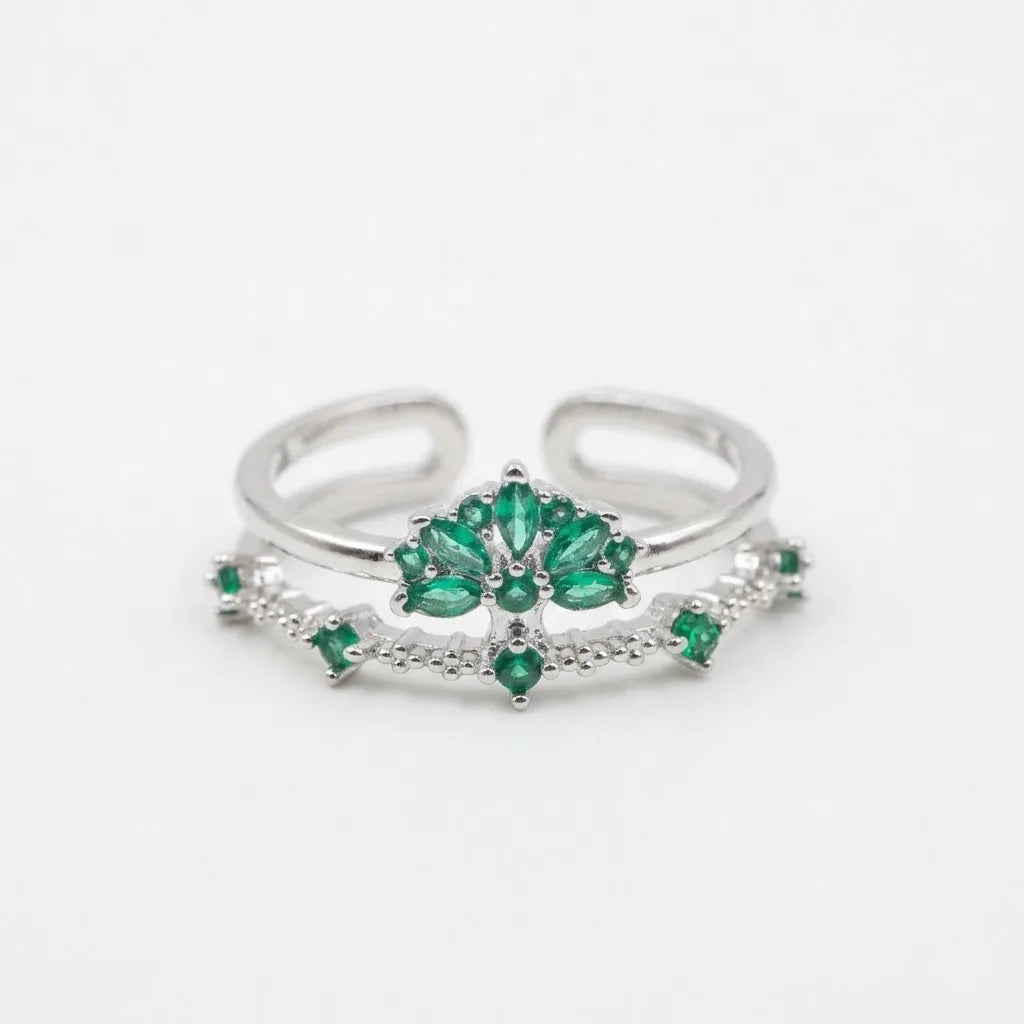 Bague ajustable argentée en acier inoxydable avec motif floral et zircons verts sur fond blanc