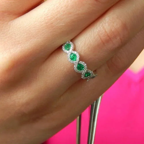  Bague alliance zircons vert émeraude portée au doigt, fond rose — Jewelry by Kitana