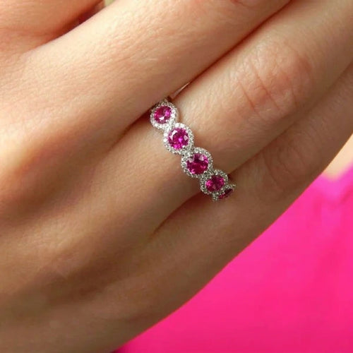 Bague alliance zircons fuchsia portée au doigt, fond rose — Jewelry by Kitana