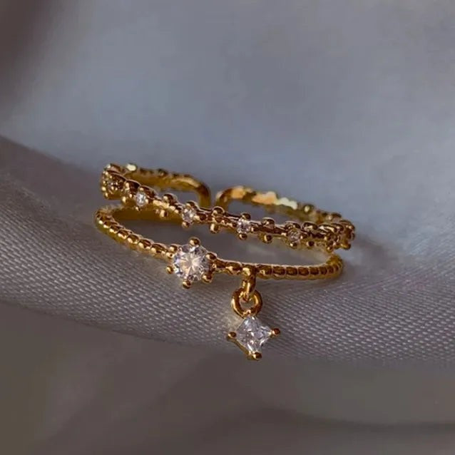 Bague Jewelry by Kitana ajustable double rang en acier inoxydable doré avec perles, zirconiums et pampille losange