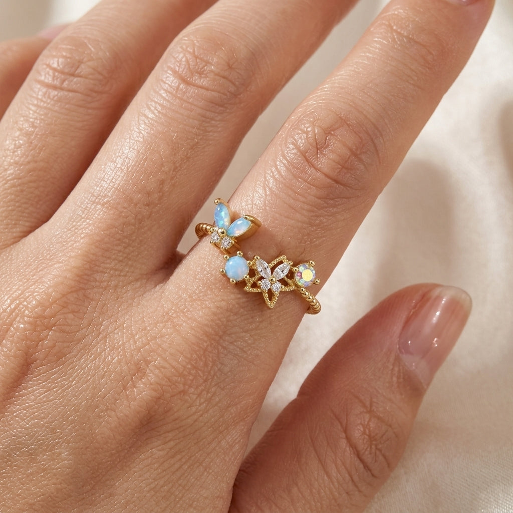 Bague ajustable plaquée or portée à la main, papillon opaline bleu azur, fleur zircons transparents et cristal irisé — Jewelry by Kitana`

