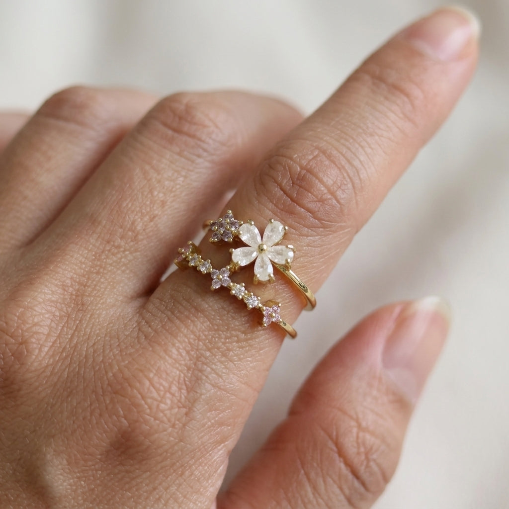 Bague double rang dorée portée au doigt, fleur nacre blanche et étoiles en zircons scintillants, style romantique – Jewelry by Kitana
