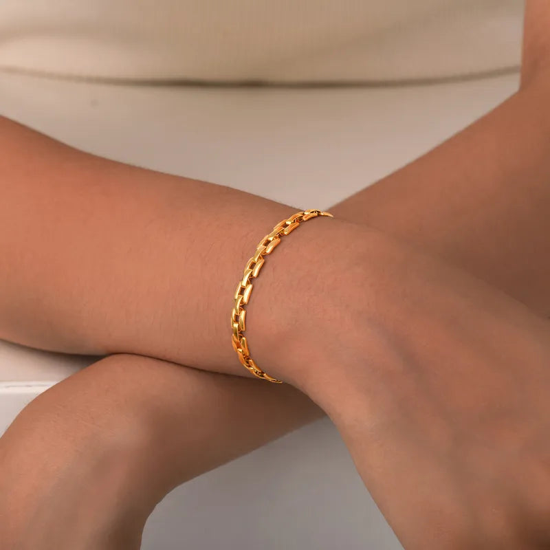 Gros plan sur un bracelet doré plaqué or 18K porté au poignet, maille rectangulaire lumineuse