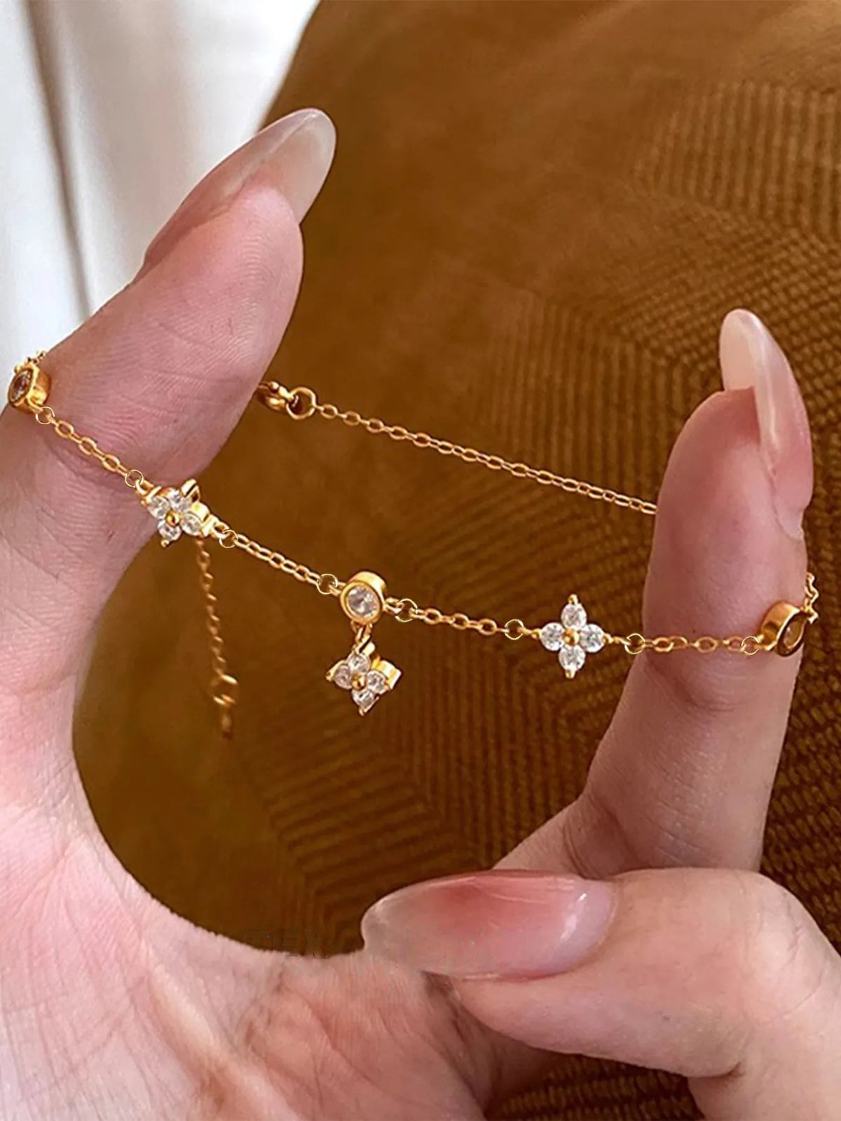 Bracelet doré fin à fleurs en zircons, fermoir à boucle visible sur le poignet