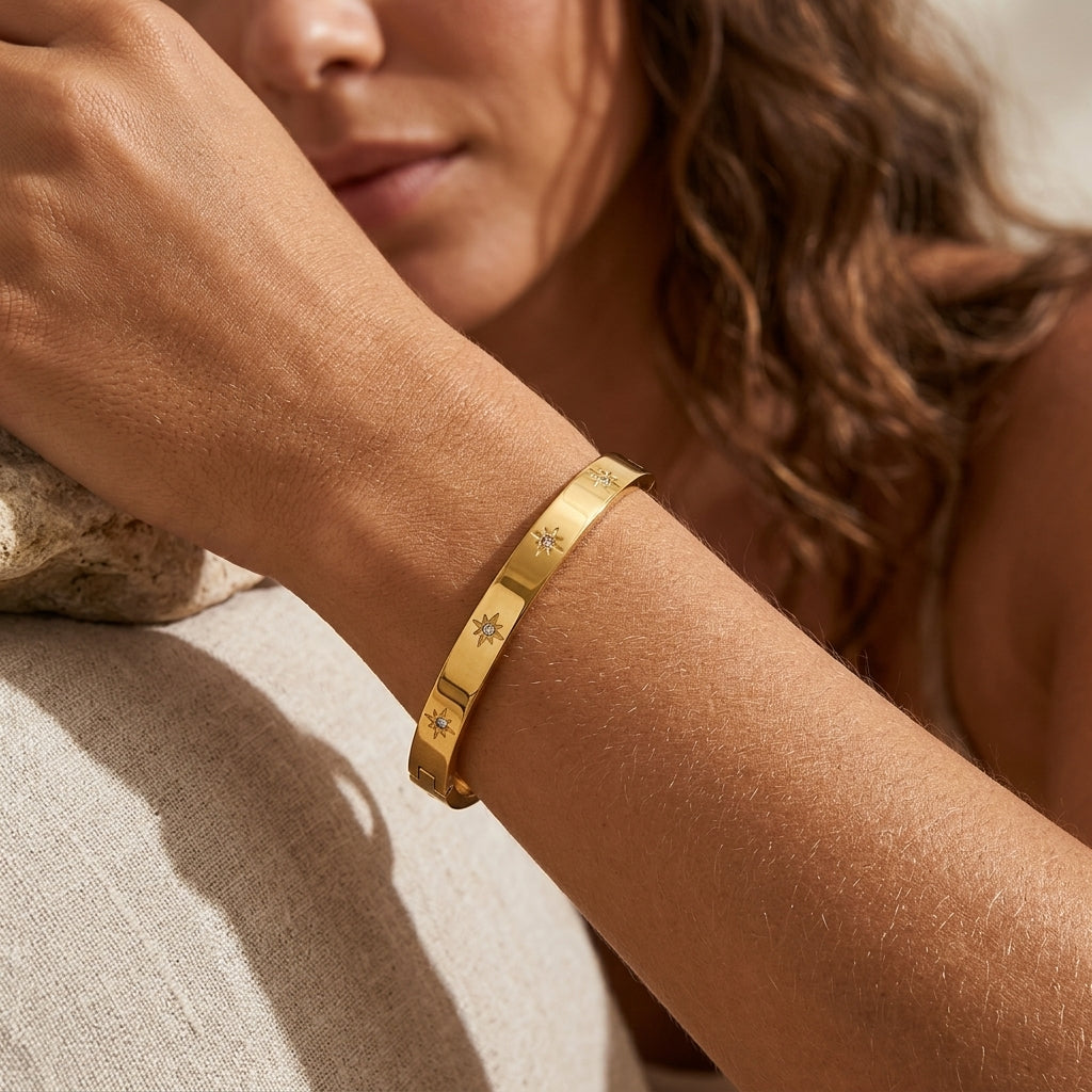 Bracelet jonc doré à motifs étoiles et zircons porté au poignet