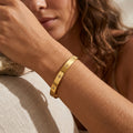 Bracelet jonc doré à motifs étoiles et zircons porté au poignet