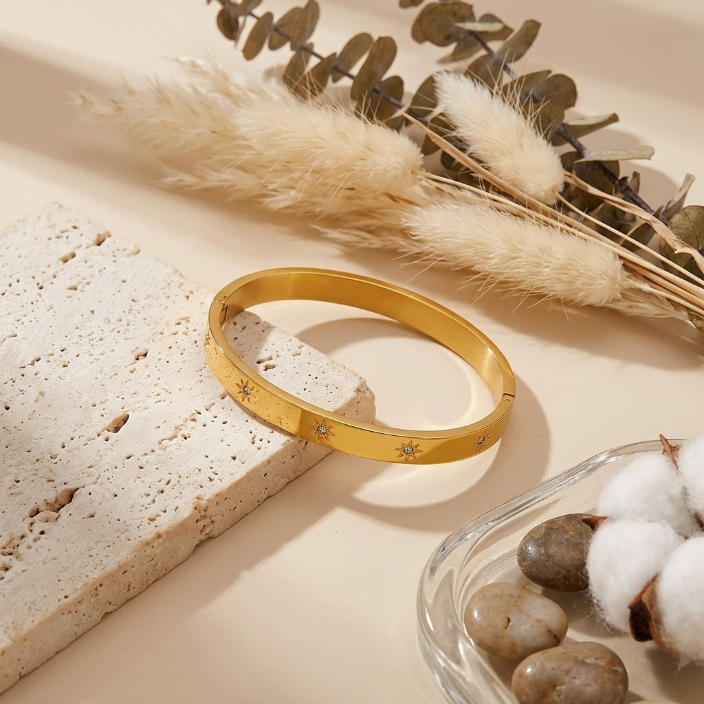 Bracelet jonc doré avec étoiles et zircons présenté sur un décor clair