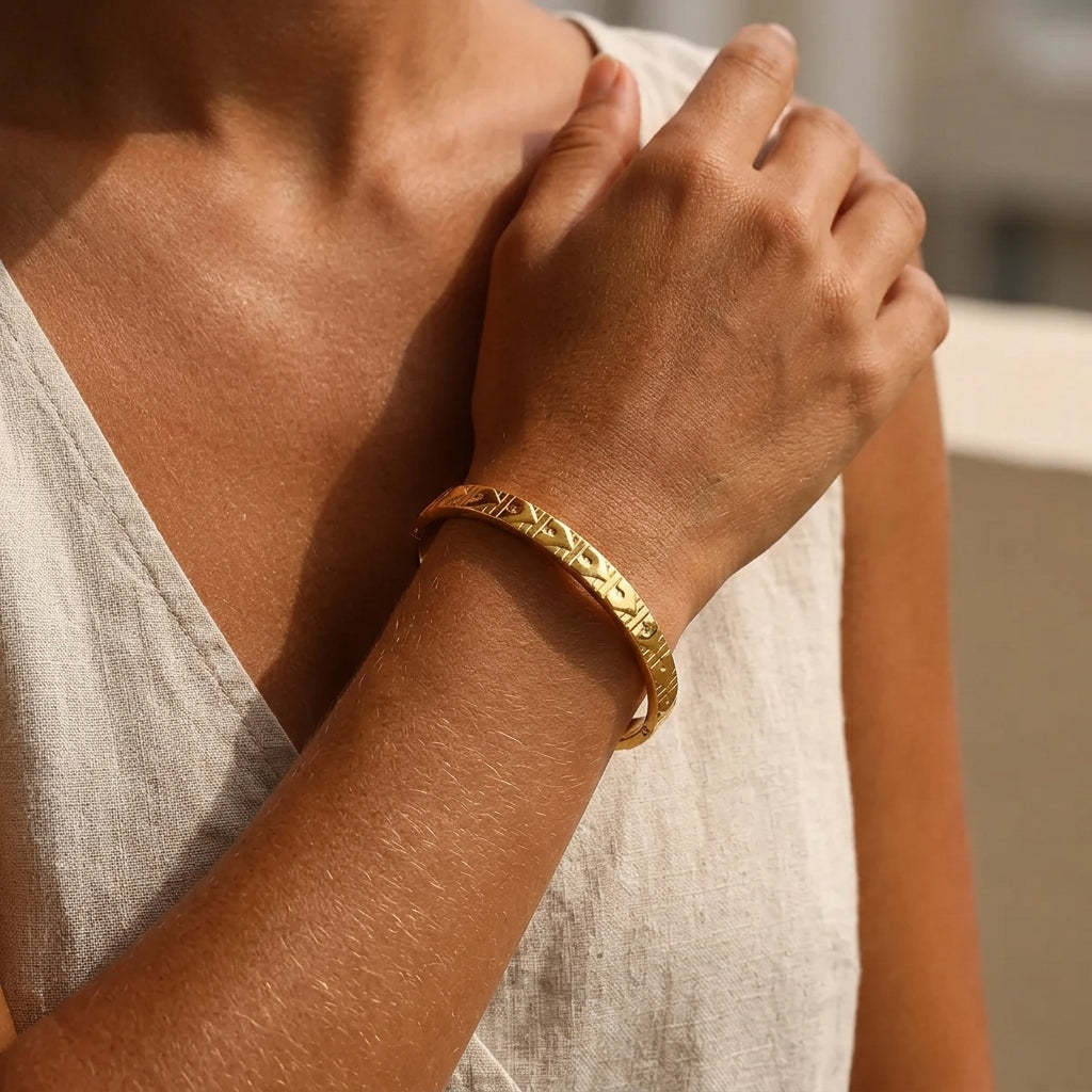 Bracelet jonc doré à motif cœur en relief porté au poignet