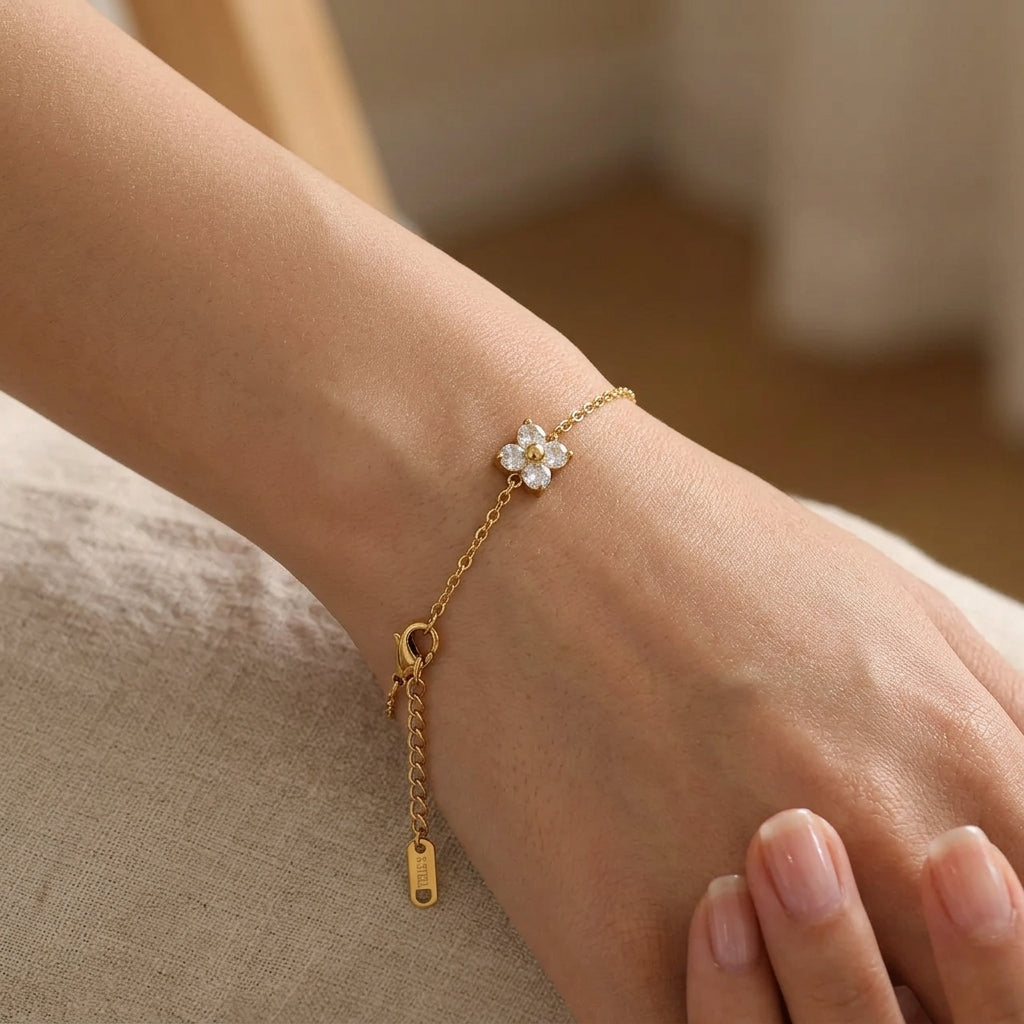 Bracelet plaqué or porté au poignet, pendentif fleur en zircons blancs brillants, chaîne fine dorée et fermoir mousqueton réglable