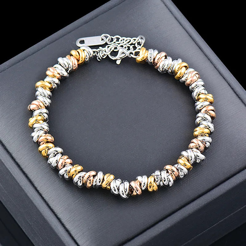 Bracelet tricolore souple en acier inoxydable doré, argenté et rose doré présenté sur un écrin noir