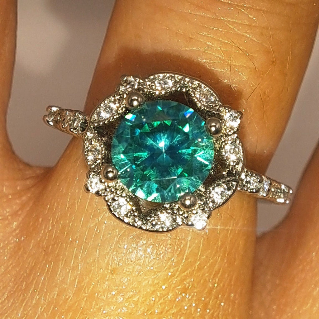 Bague argentée portée avec zircon vert d’eau rond et halo floral scintillant
jewelry by kitana 